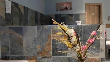 Un interno moderno con un lampadario, un vaso con fiori e una panca.