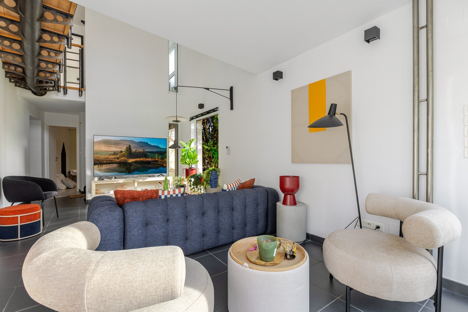 Een moderne woonkamer met een modulaire bank, twee fauteuils, een salontafel en een groot schilderij aan de muur.