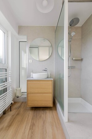 A modern bathroom with a wooden vanity, a large mirror, a glass shower enclosure, and a white radiator. - Villa Tigre | Private Sauna/Heated Spa (Quatzenheim)
