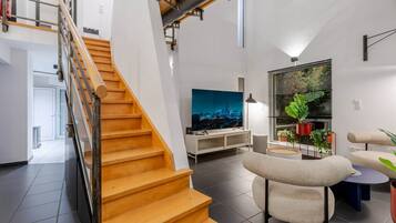 Een modern interieur met een houten trap, een flatscreen televisie en een zithoek met een ronde tafel.