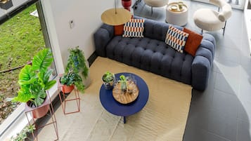 En moderne stue med en mørkegrå sofa, mønstrede puder, et rundt sofabord og krukkeplanter.