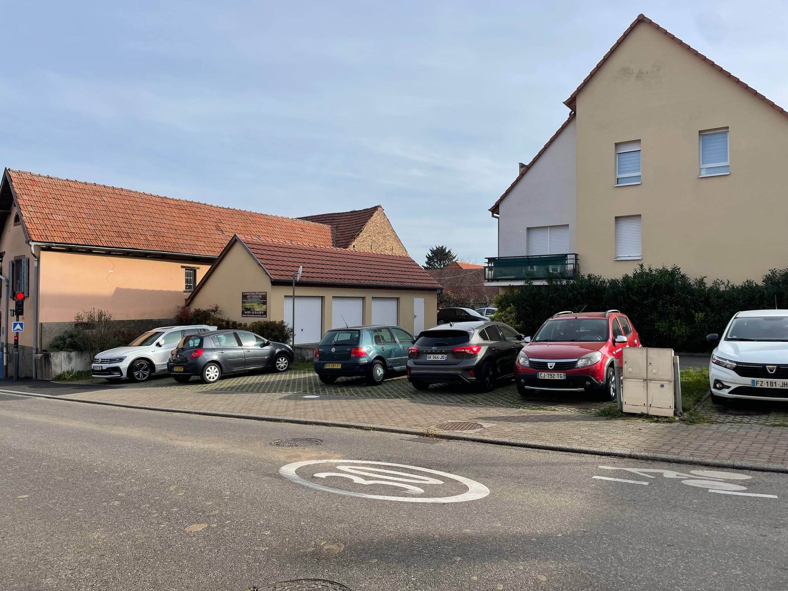 Un parcheggio con diverse auto parcheggiate di fronte a un edificio con un tetto in tegole rosse.