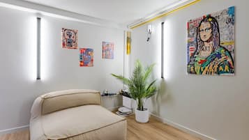 Et værelse med en sofa, en potteplante og billedkunst på væggen.
