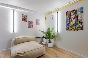 A room with a sofa, a potted plant, and wall art. - Villa Tigre | Private Sauna/Heated Spa (Quatzenheim)