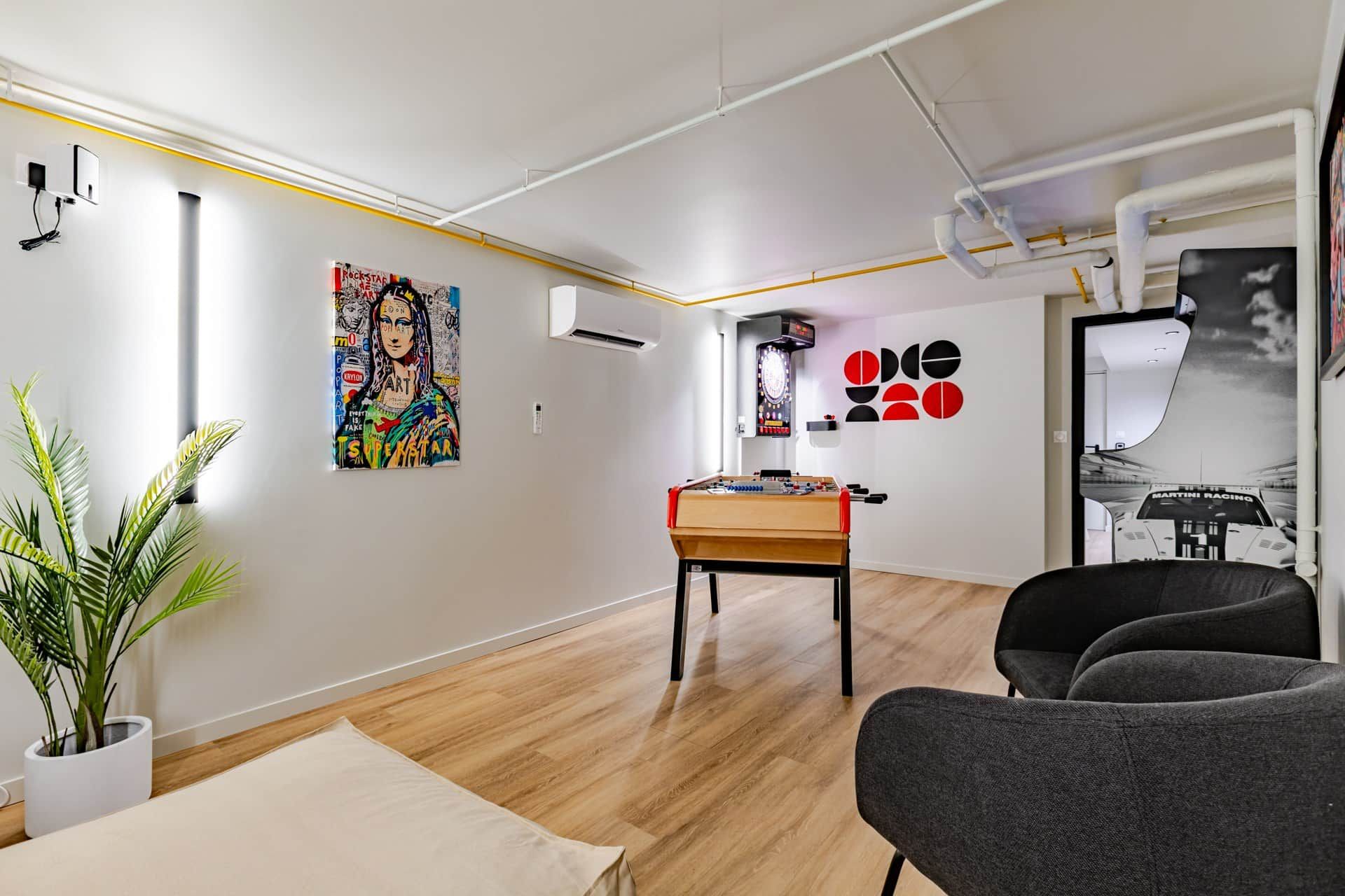 Ein modernes Zimmer mit einem Kicker, einer Wandklimaanlage und einem Rockband-Poster.