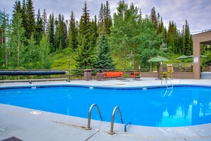 A swimming pool with a wooden deck, surrounded by a forest. - Beaver Run|Ski In/Out|Cozy Chalet|Pool & Hot Tub (Breckenridge)