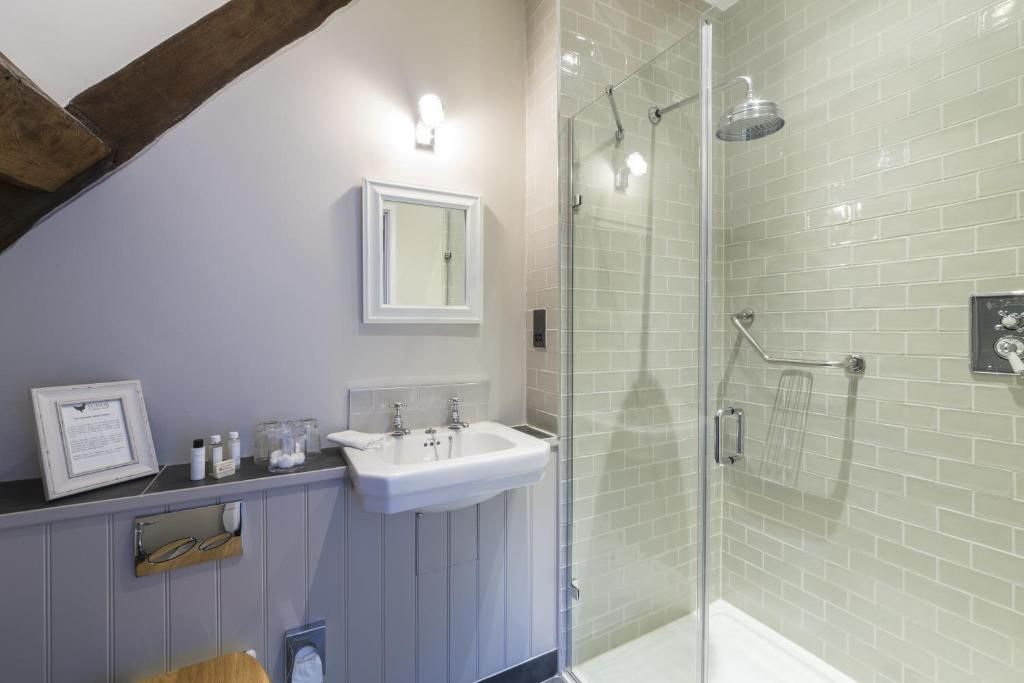 Un baño con ducha envuelta en cristal, un lavamanos y un espejo.