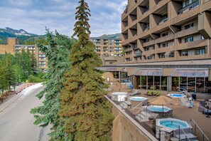 Ein Hotel mit mehreren Etagen, Außenpools und einer Bergkulisse.