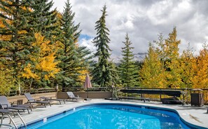 Ein Swimmingpool mit Liegestühlen und Blick auf Bäume und Berge.