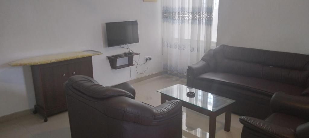 A living room with a sofa, a coffee table, and a TV mounted on the wall.