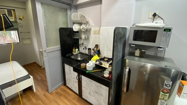 Una cocina compacta equipada con microondas, refrigerador y lavamanos.