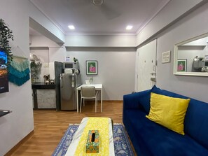 A compact living space with a kitchenette, a dining area, and a sofa with a yellow pillow.