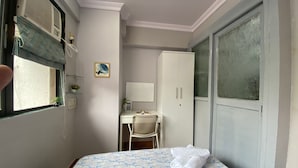 Habitación de hotel con cama, escritorio, silla, armario y ventana con persianas.