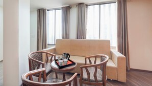 A modern living room with a sofa and two wooden chairs, a coffee table with a tray, and a window with curtains. - Collection O Motipura Bus Terminal (Himatnagar)