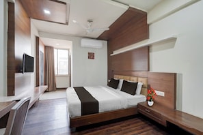 Una camera d'albergo con un letto, un comodino, una TV e una ventola a soffitto.
