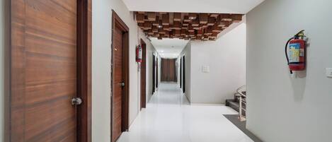 Un pasillo con puertas de madera, un extintor y una escalera.