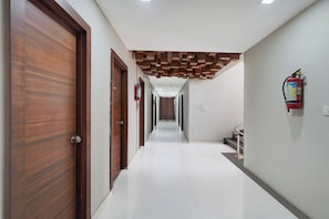 A hallway with wooden doors, a fire extinguisher, and a staircase.