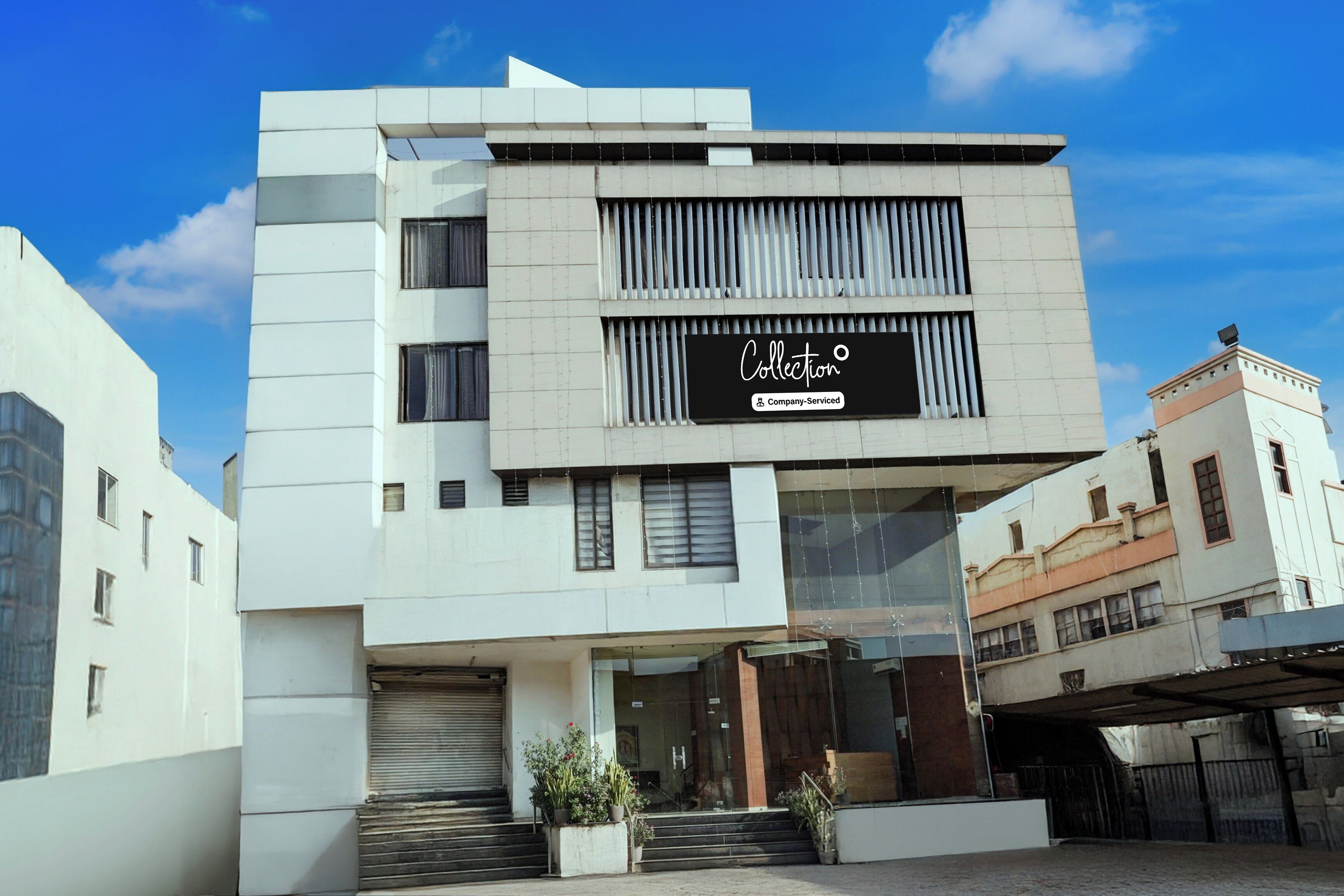 Un edificio moderno con un llamativo letrero 'Collection', amplias ventanas y un cielo despejado.