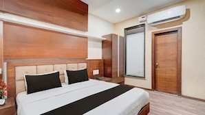 A hotel room with a bed, a bedside table with a phone, a wardrobe, and an air conditioning unit. - Collection O Motipura Bus Terminal (Himatnagar)
