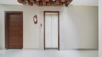 Ein Zimmer mit einer Holztür, einem weißen Aufzug und einem an der Wand befestigten Feuerlöscher.