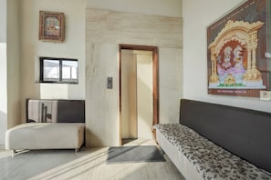 A room with a sofa, a bed, a door, and a wall-mounted picture.