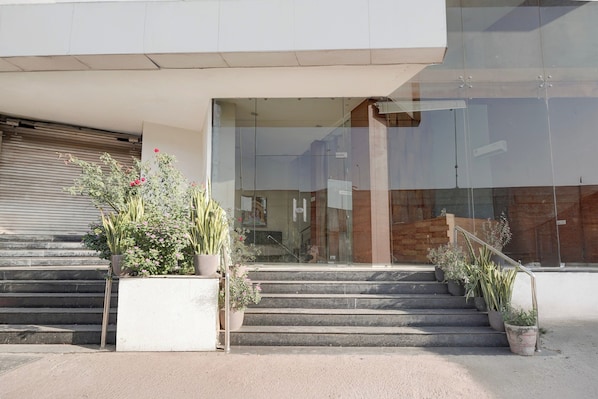 A modern building entrance with glass doors, a reception area, and a staircase leading up.