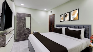 Habitación de hotel con una cama, televisión, armario, puerta y obras de arte en la pared.