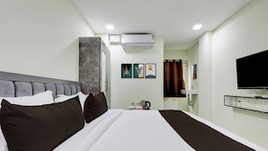 Habitación de hotel con una cama grande, un televisor de pantalla plana, una cafetera y obras de arte en la pared.