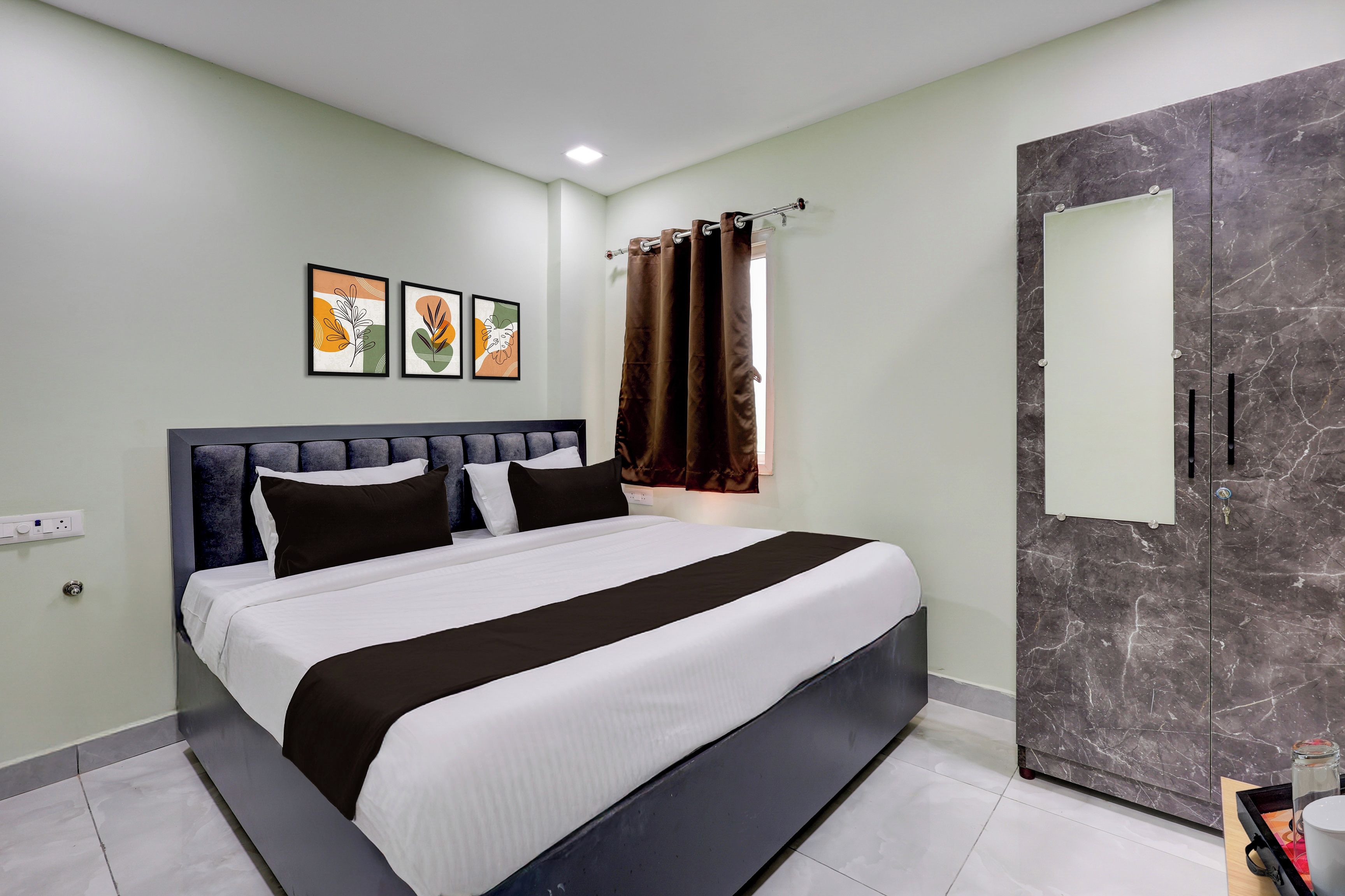 A modern bedroom with a bed, a wardrobe, and artwork on the wall.