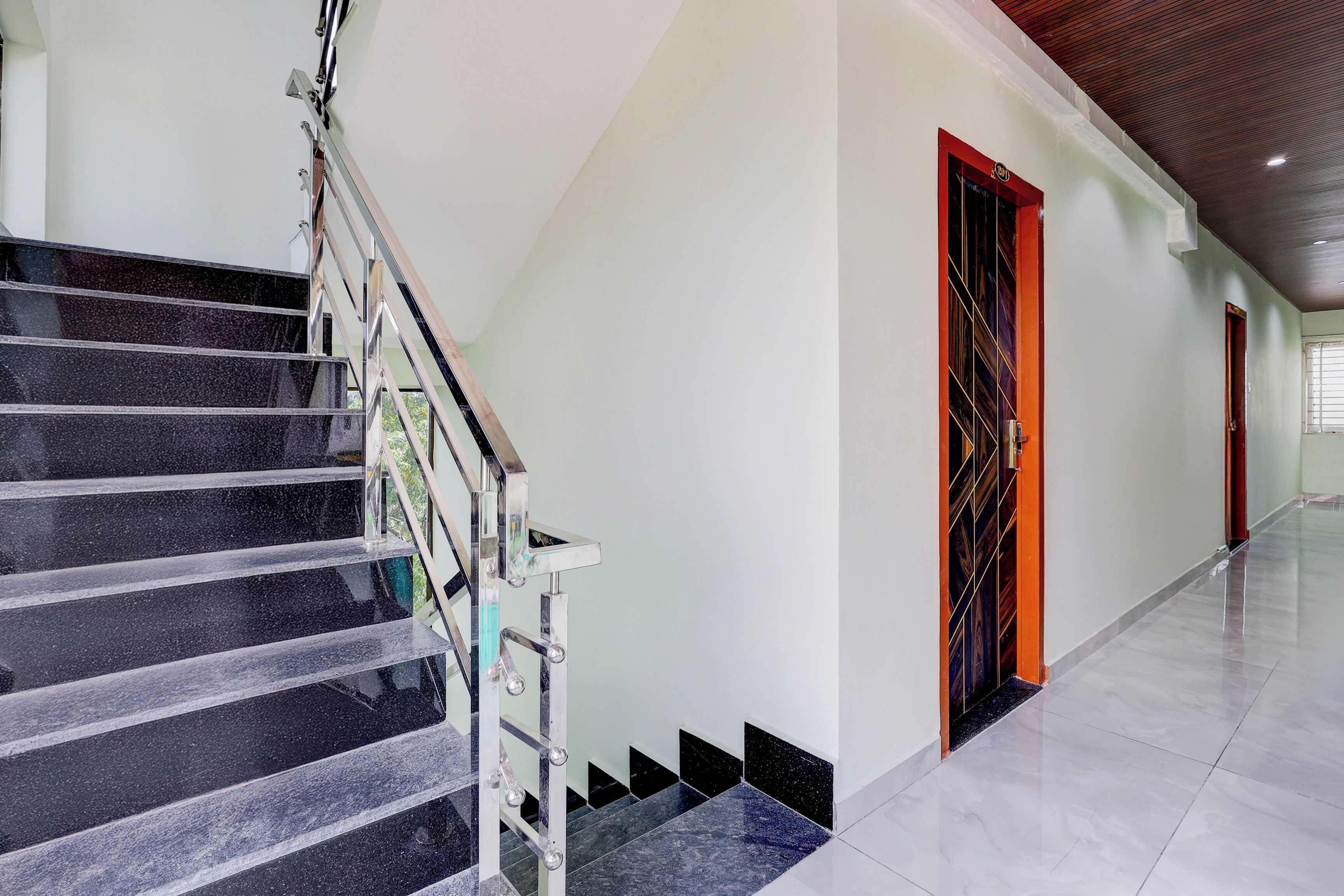 A modern interior with a marble staircase, a hallway with doors, and a tiled floor.