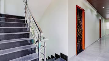 A modern interior with a marble staircase, a hallway with doors, and a tiled floor.