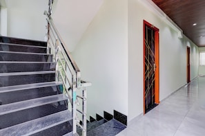Un interior moderno con una escalera de mármol, un pasillo con puertas y un suelo de baldosas.