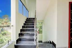 Una escalera con escalones negros y barandilla de metal que conduce a una puerta con marco rojo.