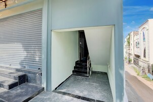 Eine Treppe führt zu einer oberen Etage, mit einer Metalttür und Blick auf eine Straße mit Gebäuden.