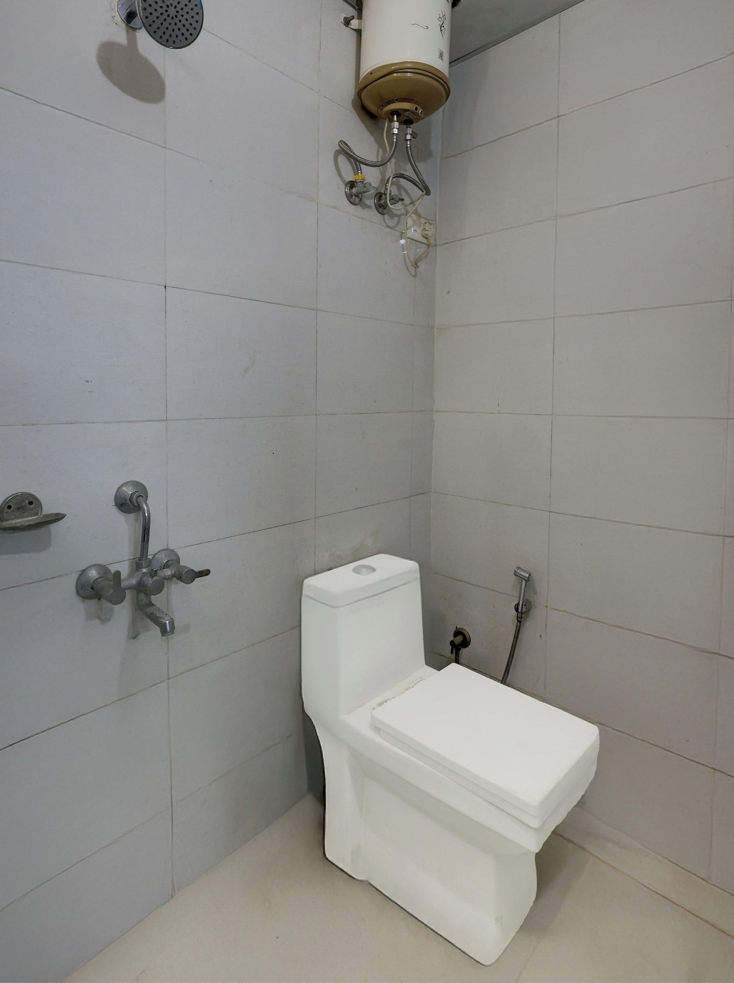 A bathroom with a toilet, a shower, and a toilet paper holder.