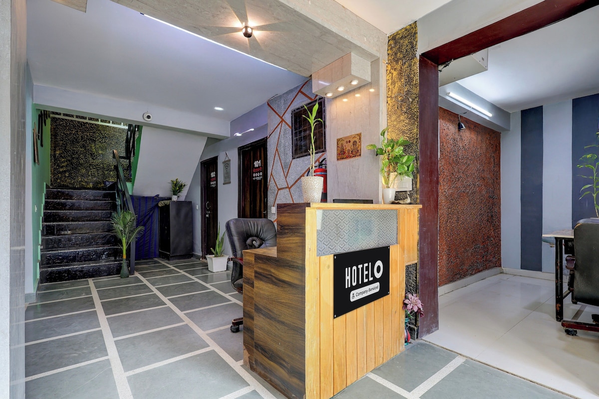 Uma área de recepção de hotel com balcão de madeira, escada e parede com textura.