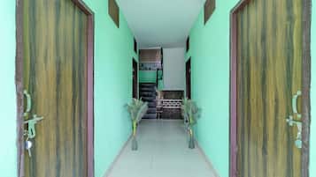 A corridor with two wooden doors on either side, leading to a room with a tiled floor and a small staircase.