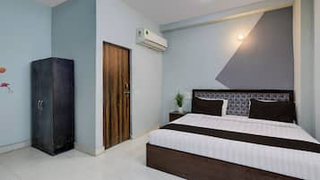 A bedroom with a bed, a wardrobe, an air conditioning unit, and a wall-mounted light fixture.