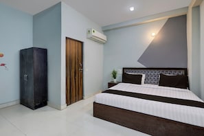 Quarto com cama, guarda-roupa, ar condicionado e luminária na parede.