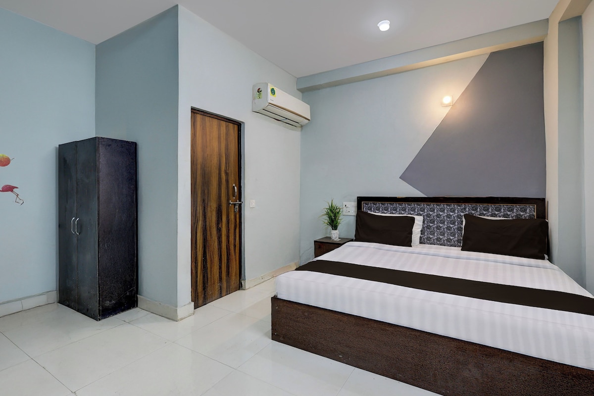 A bedroom with a bed, a wardrobe, an air conditioning unit, and a wall-mounted light fixture.