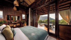 A bedroom with a large bed, a wooden dresser, a mirror, and a view of the outdoors. - Lamia Tropical Garden (Tay Hoa Lu)
