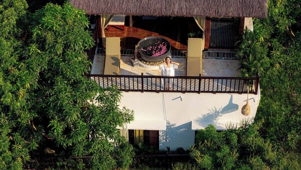 A thatched-roof structure with a circular water feature and a balcony. - Lamia Tropical Garden (Tay Hoa Lu)
