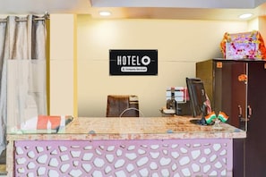 Een receptiebalie van een hotel met een bord waarop 'HOTELO Company Serviced' staat.