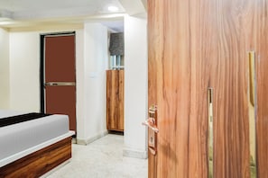 Een slaapkamer met een bed, een houten garderobe en een deur.
