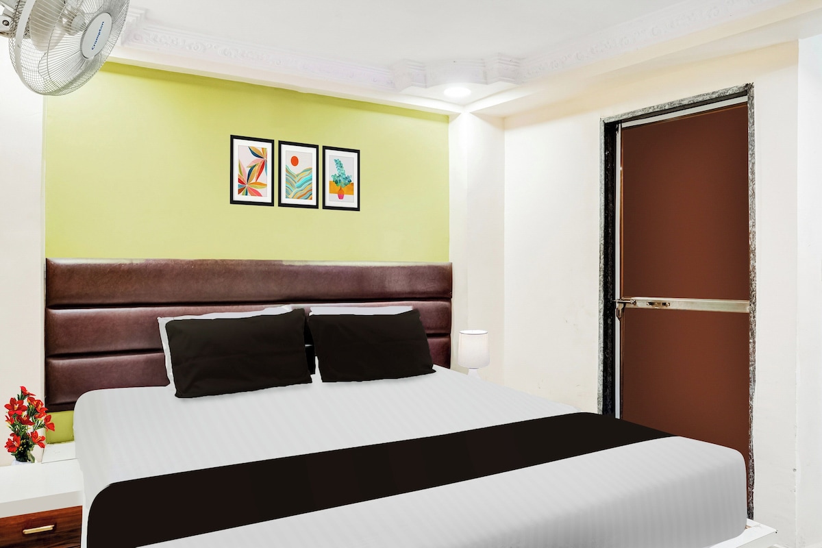 Een hotelkamer met een bed, een nachtkastje, een lamp en twee ingelijste kunstwerken aan de muur.