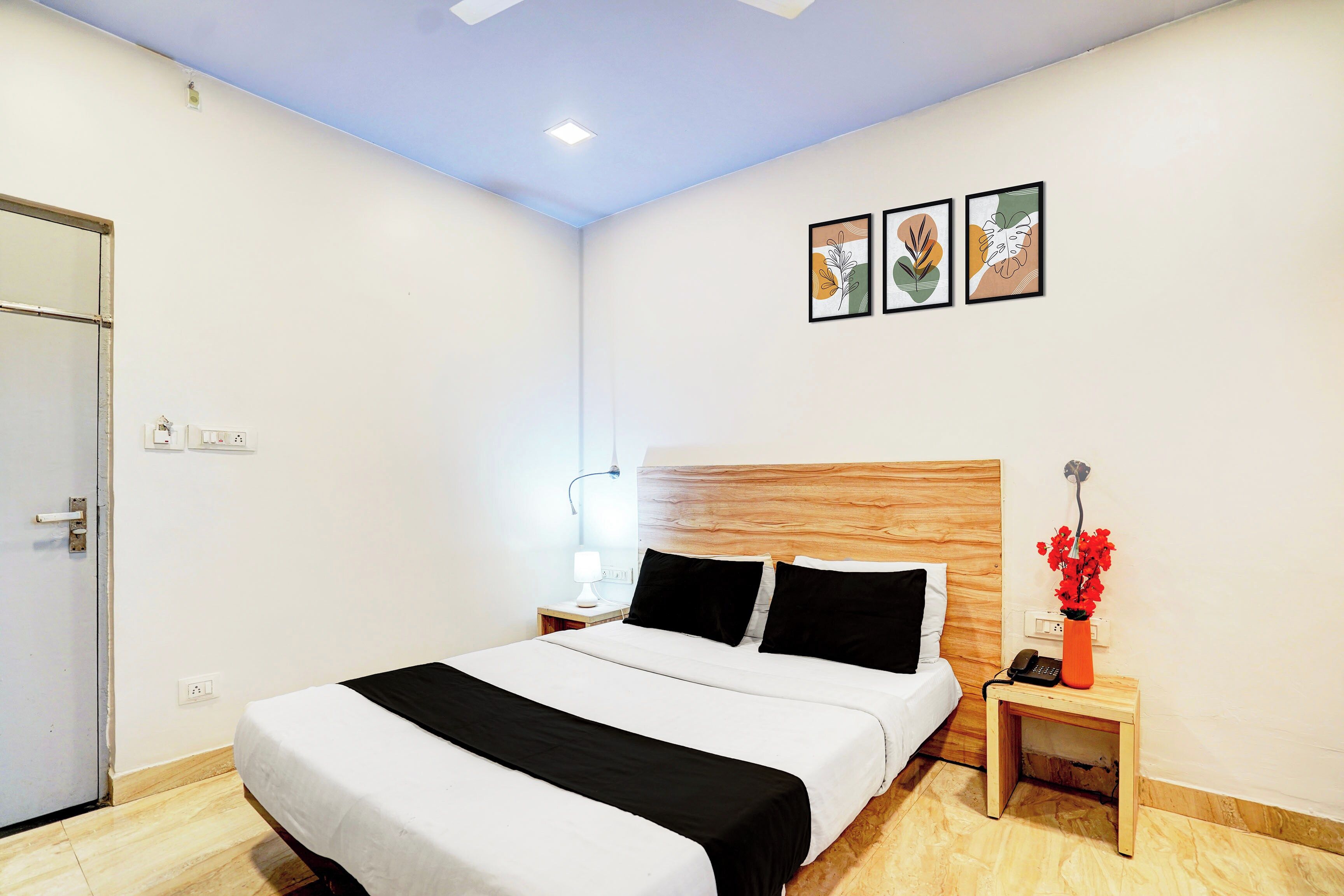 Ein Hotelzimmer mit Bett, Nachttisch, Lampe und einem an der Wand befestigten Telefon.