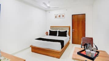 Un dormitorio con cama, mesita de noche con bandeja, puerta y ventilador de techo.