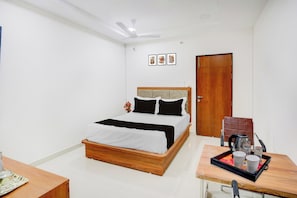 A bedroom with a bed, a bedside table with a tray, a door, and a ceiling fan. - Townhouse Hanamkonda Formerly Vishnu  (Hanmakonda)