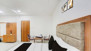 Habitación de hotel con cama, armario de madera, escritorio con silla y estante en la pared.