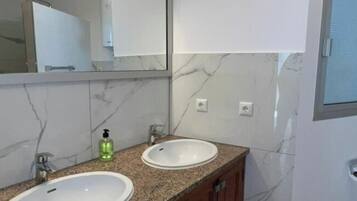 Un baño con dos lavamanos, un espejo y una ventana.